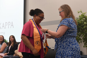 A PTK student wears a golden sash and receives an award. 