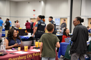 An individual and a child attend a Brightpoint career fair and speak to a smiling employer. 