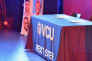 The VCU NEXT Step signing table placed next to a podium with a microphone and a Brightpoint logo on it. 