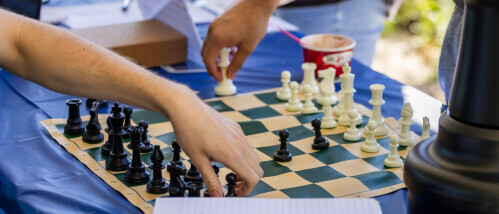 Hands move pieces on a black-and-white chess board.