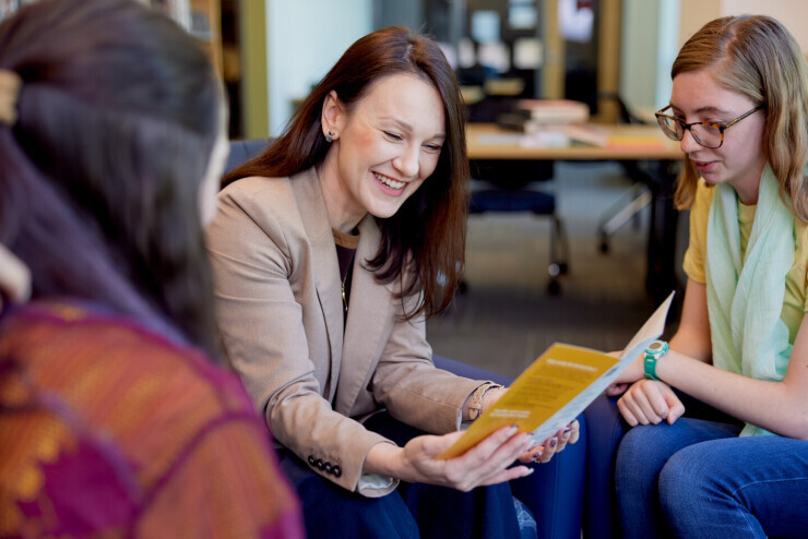 An advisor smiles while speaking to two students about transferring to a four-year university.