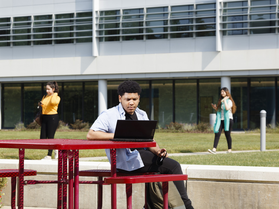 Student on laptop in Midlothian courtyard