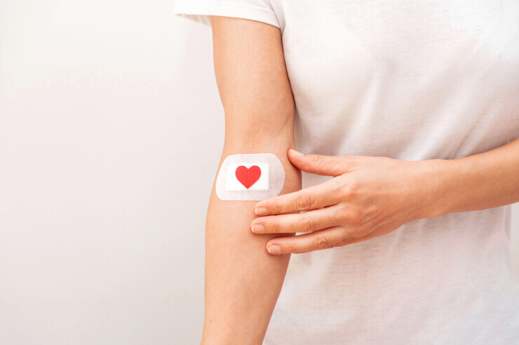 links to An arm wears a white bandage with a red heart on it. 