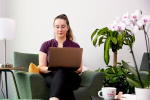 A person looks at their laptop while seated in a comfortable chair at home.