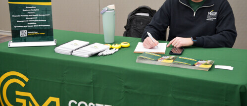 GMU representative sits at an information table.