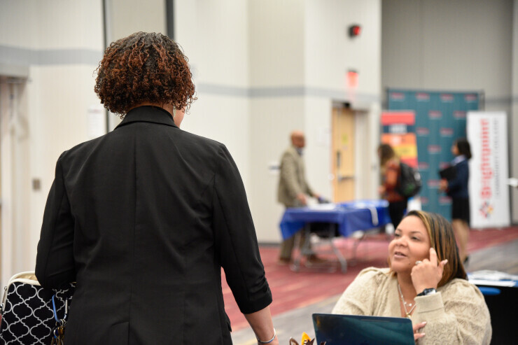 links to A person in a blazer speaks to a professional at a Brightpoint event. 