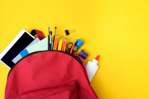Red back spilling out school supplies on a yellow background.