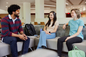 Three students sit on couches at the Brightpoint campus, smiling and chatting. 