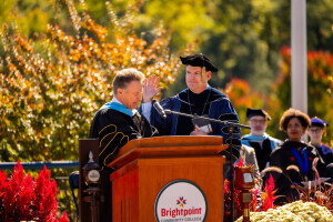 Two people stand behind a podium during an outdoor event