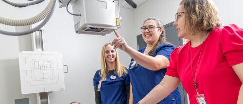 Brightpoint Radiology students smile as they test equipment with a professor.