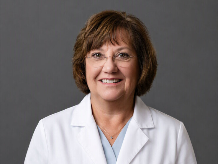 Headshot of Dr. Nancy Leahy wearing a white lab coat on gray background