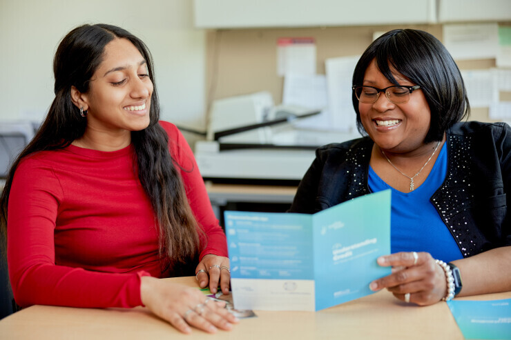 links to A Financial Aid advisor shows a pamphlet to a smiling student. 