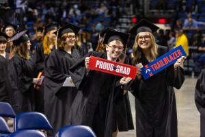 Brightpoint graduates wear caps and gowns and hold signs that say, 