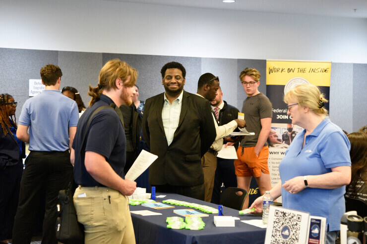 An employer representative smiles among a diverse group of attendees at a Midlothian Campus career fair. 