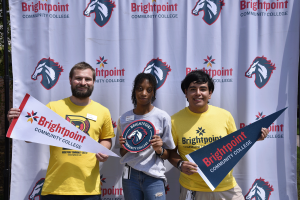 A Brightpoint staff member and student ambassadors pose in front of a trailblazer banner. 