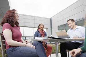 Three students talking while sitting in an outdoor class space