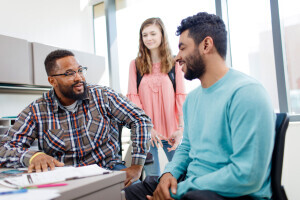 An advisor discusses paperwork with smiling students. 