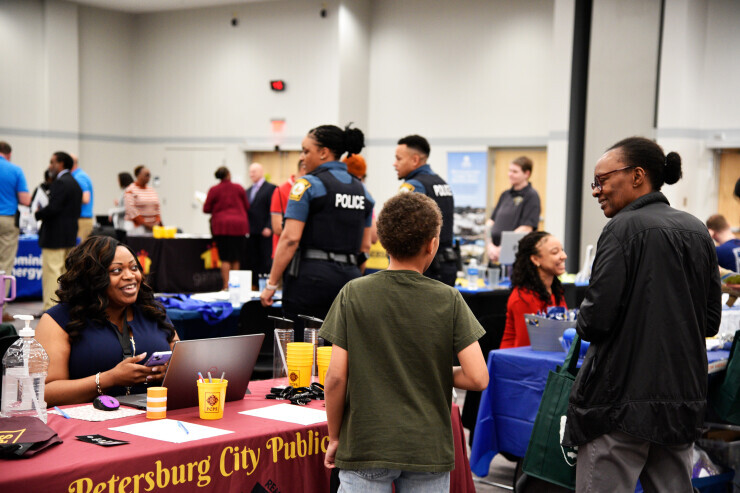 links to An employer at a booth smiles while talking to a Chester career fair attendee and a child. 
