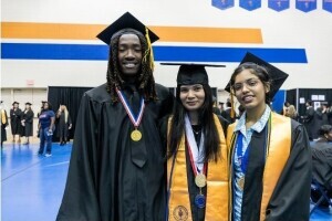 A diverse group of Brightpoint graduates smile while wearing their caps and gowns. 