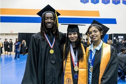 A diverse group of Brightpoint graduates smile while wearing their caps and gowns. 