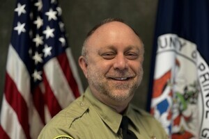Rob Leinberger wears his Prince George County animal control uniform and poses in front of the U.S. and Prince George County flags. 