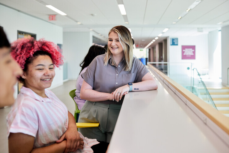 links to Students smile while having a conversation inside Trailblazer Hall.