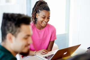 A person smiles at their laptop.