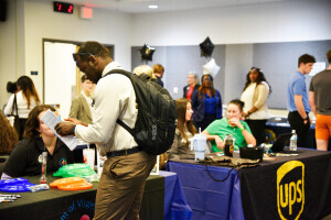 A person wearing business casual clothing reviews their resume while in front of employer booths at a Midlothian Career Fair. 