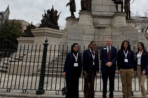 Brightpoint students and the college president stand in front of the base of a statue at the State Capitol