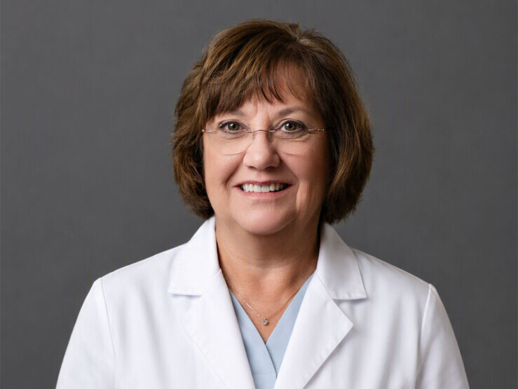 Headshot of Dr. Nancy Leahy wearing a white lab coat on gray background