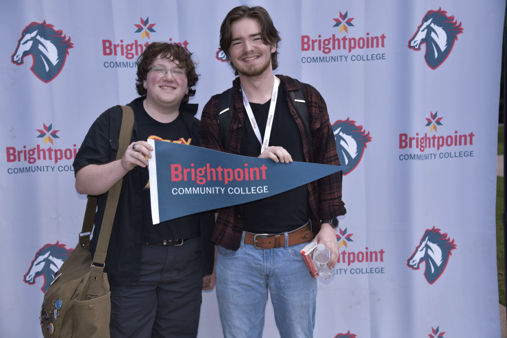 links to Two students pose in front of a trailblazer banner while holding a Brightpoint flag. 
