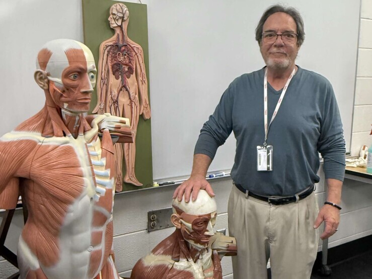 Rick Sikon in a classroom at the Chester Campus surrounded by 3D anatomical models of muscle, bone and veins. 