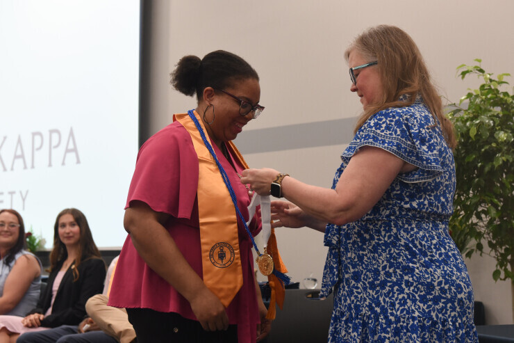 links to A PTK student wears a golden sash and receives an award. 