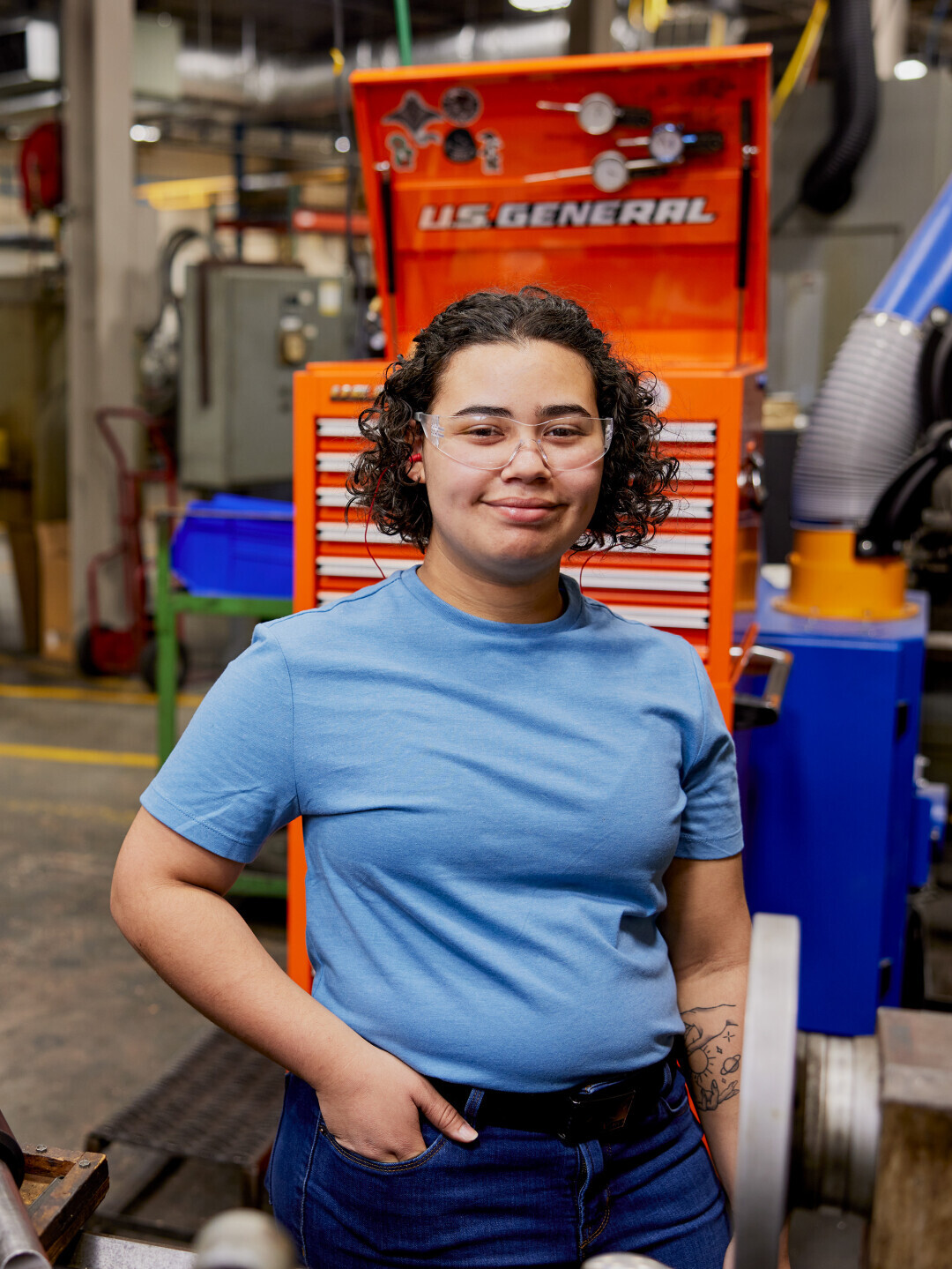Brightpoint alum Heilie Sheppard smiles while standing in front of machinery. 